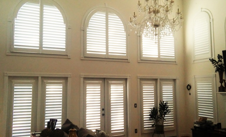 Family room in open concept Minneapolis home with plantation shutters on high ceiling windows.