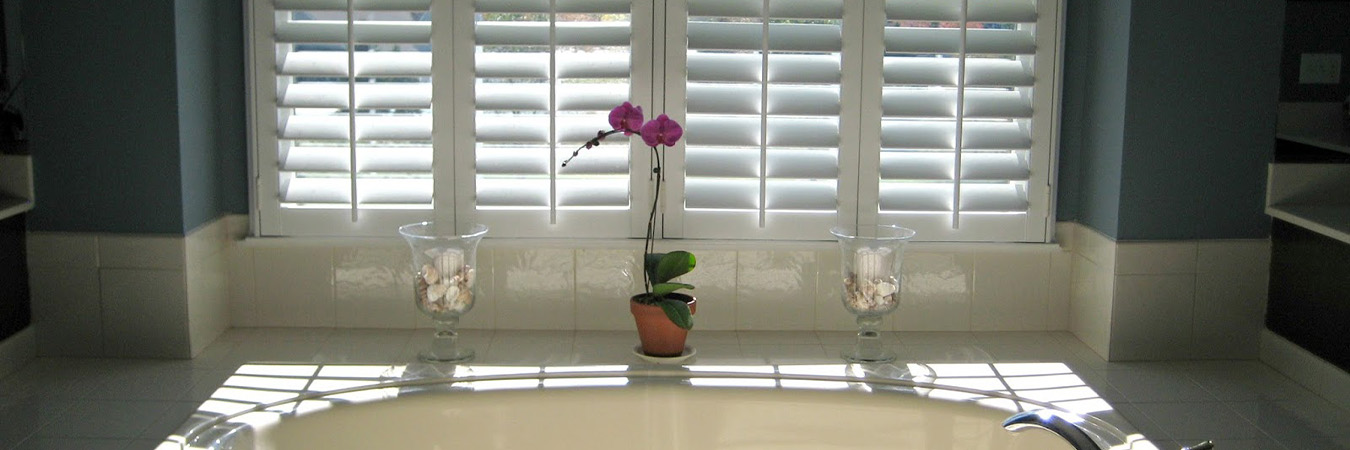 White Polywood shutters above a bath tub.