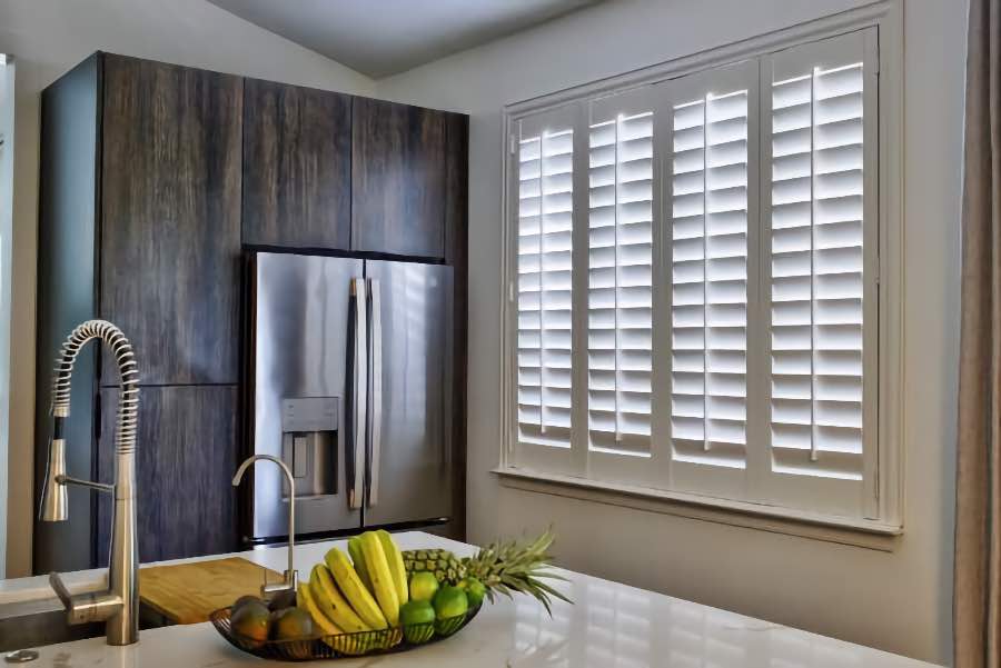 Homeowners use indoor window shutters in Minneapolis when they want attractive and functional window treatments. Polywood shutters on a large kitchen window
