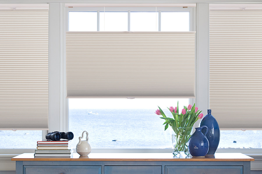 Blue chest of drawers inform of a casement window covered by neutral colored cellular shades