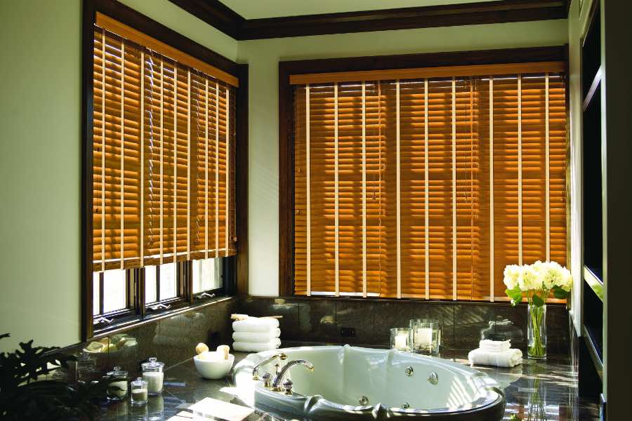 Premium quality blinds are always a stylish accent in your Minneapolis home. Brown wood blinds on large windows in a green bathroom