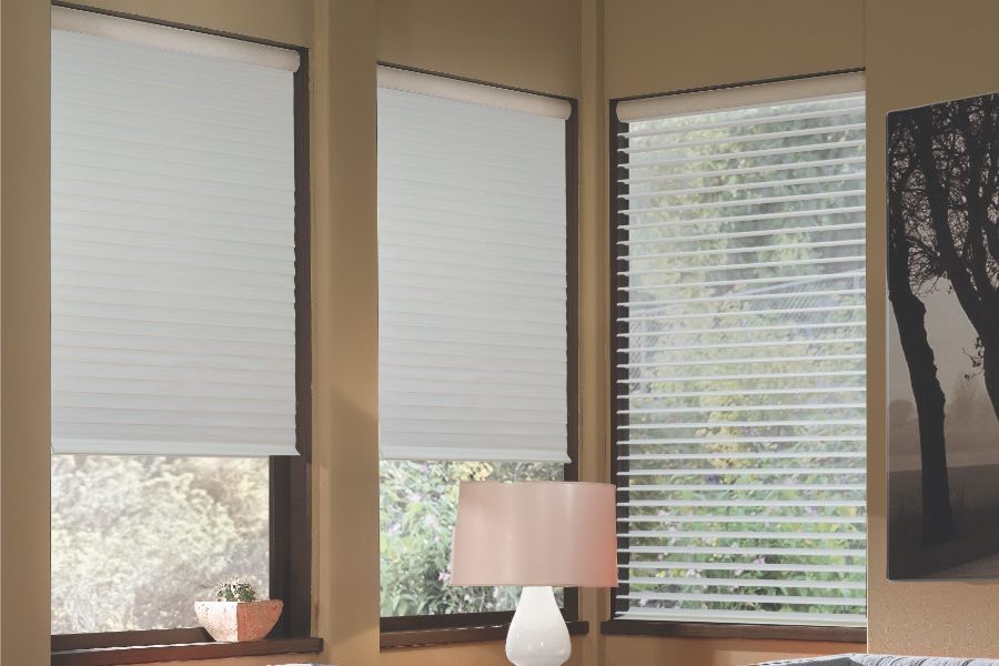 Opaque motorized window shades in Minneapolis keep hot UV rays out of your home. Gray motorized sheer shades on corner windows next to gray furniture