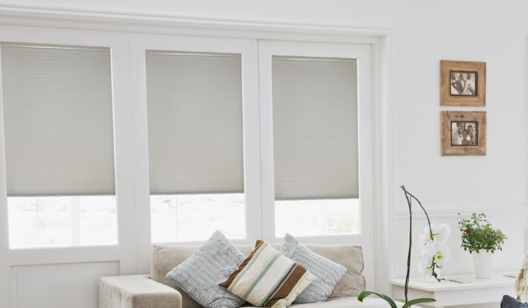 Cellular window shades provide room temperature control with a softer look. Cellular shades in a living room.