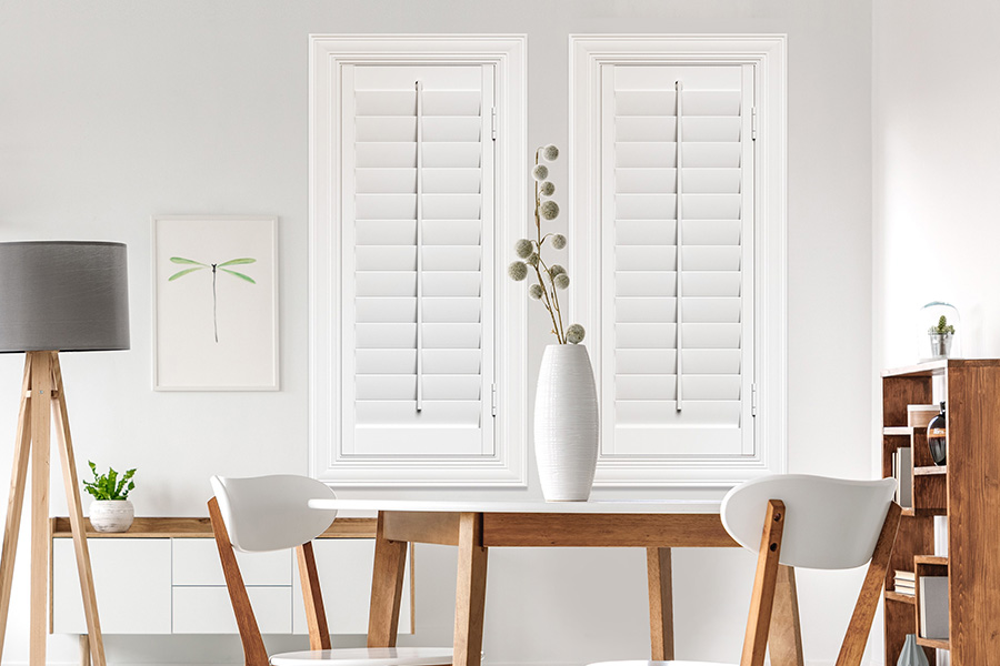 Sunburst's selection of stylish window treatments for designers in Minneapolis makes it easy to find the perfect ones for every design job. White Polywood shutters on two windows in a modern Scandinavian-style room