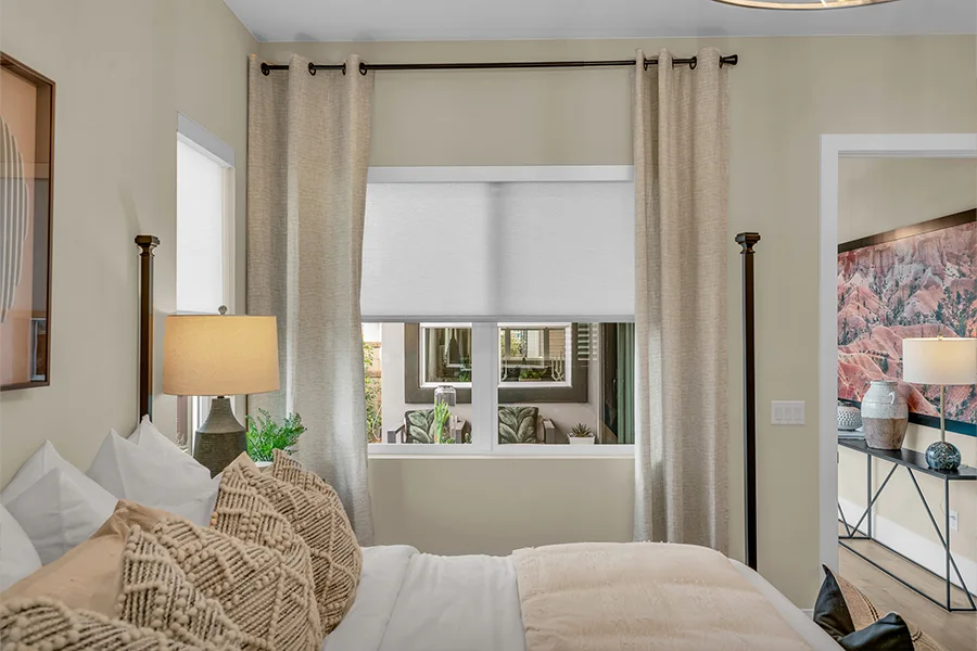 Beige drapes and a white window shade in a beige bedroom