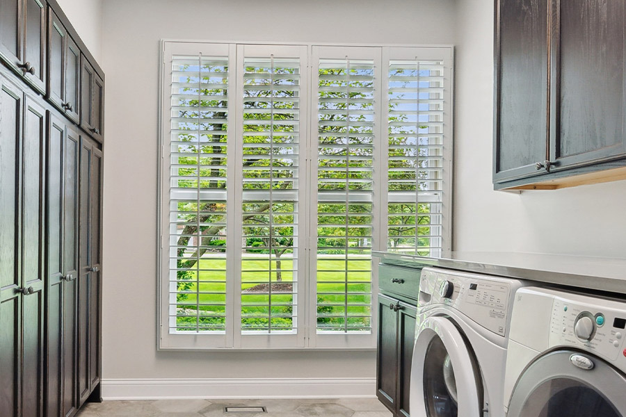 Find the perfect level of natural light for your Minneapolis laundry room with interior shutters. White Polywood shutters letting light through a laundry room window