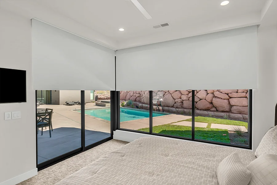 Motorized white window shades covering large bedroom windows